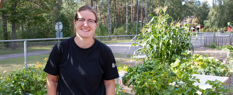 Kvinna står framför odlingsbäddar.