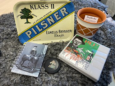 Varor från butiken, museets eget sortiment såsom pilsnerbricka, Albert Engström-servetter och putsduk
